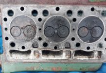 Understanding Marine Diesel Engines image of The underneath of the engine head showing the top of the three cylinders. Each has two valves-one opens to let air in and the other lets exhaust gases out. Seawater has got into the left hand one. Underneath there is a thick off white cream coloured mixture of oil and seawater.